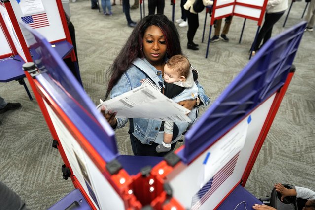 First-time voter Kayria Hildebran holds baby Kayden Hildebran as she fills out her ballot during in-person early voting at Hamilton County Board of Elections, Thursday, October 31, 2024, in Cincinnati. (Photo by Carolyn Kaster/AP Photo)