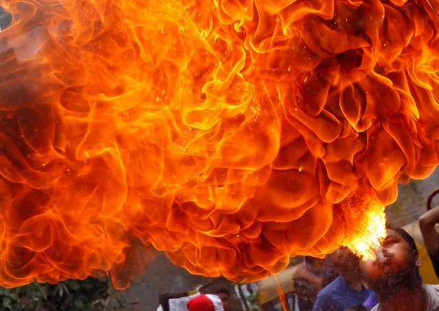 A Hindu devotee performs a stunt with fire during a rehearsal for the annual Rath Yatra, or chariot procession, which commemorates a journey by Hindu god Jagannath, his brother Balabhadra and sister Subhadra, in specially made chariots, in Ahmedabad, India, June 26, 2016. (Photo by Amit Dave/Reuters)