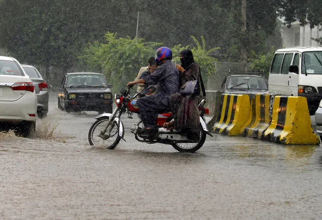 A Pakistani couple ride their motobike in heavy rain fall in Islamabad, Pakistan, Wednesday, August 5, 2015. (Photo by Anjum Naveed/AP Photo)