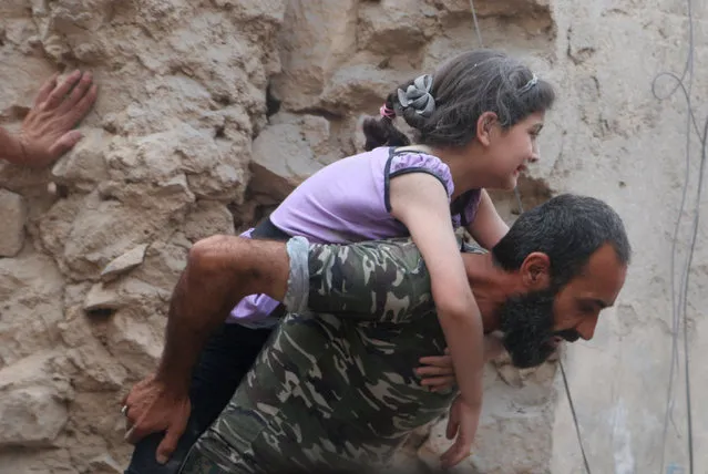 A man carries an injured girl after an airstrike on Aleppo's rebel held Kadi Askar area, Syria July 8, 2016. (Photo by Abdalrhman Ismail/Reuters)