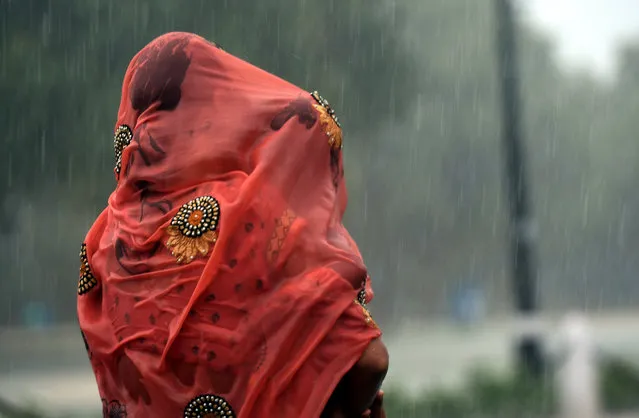 An Indian woman covers her baby under her saree during heavy rain at Rajpath in New Delhi on August 7, 2017. (Photo by Prakash Singh/AFP Photo)