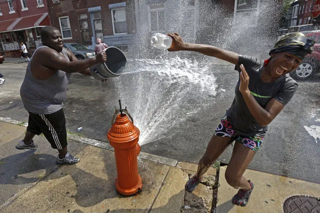 Residents play in water during afternoon heat in Philadelphia, USA on July 18, 2012. (Photo by Matt Rourke/AP)