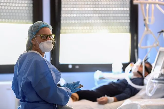 A medical worker wearing a protective mask and suit looks on as she treats a patient suffering from coronavirus disease (COVID-19) in an intensive care unit at the Oglio Po hospital in Cremona, Italy March 19, 2020. (Photo by Flavio Lo Scalzo/Reuters)