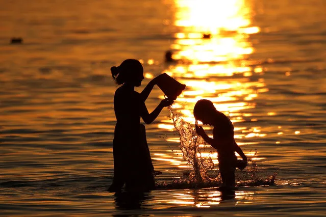 Children cool off during sunset as temperatures rise in Vlora, Albania on July 16, 2022. (Photo by Florion Goga/Reuters)
