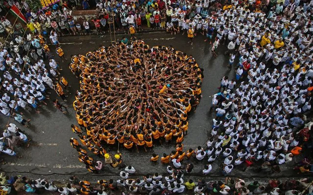 Indian devotees pray before forming a human pyramid to reach and break a “dahi-handi” (curd-pot), on occasion of the Janmashtami Festival in Mumbai, India, 18 August 2014. Hindu devotees take part in the celebration in which an earthen pot is suspended high above the ground and groups of young men and children form a human pyramid to reach the pot and break it. The festival celebrates the birth of Hindu god Lord Krishna, one of the most popular gods in Hinduism. (Photo by Divyakant Solanki/EPA)