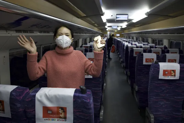 A passenger wearing a face mask to protect against the spread of new coronavirus talks about how happy she is to leave her 76-day stay in lockdown in Wuhan as she boards the first high-speed train to leave Hankou train station after the resumption of train services in Wuhan in central China's Hubei Province, Wednesday, April 8, 2020. (Photo by Ng Han Guan/AP Photo)