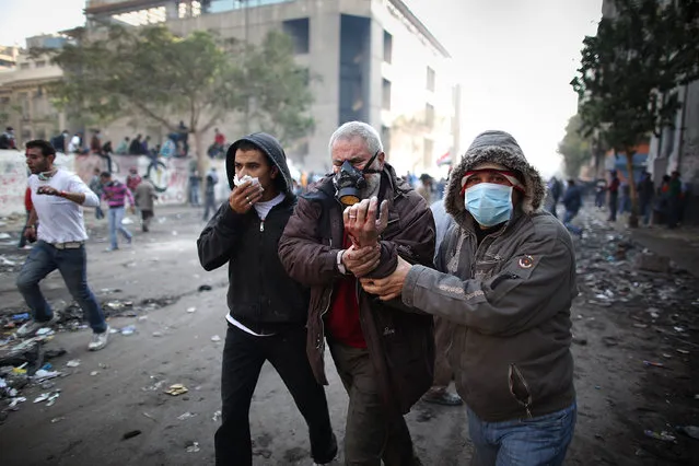 An injured protestor  is led away during clashes with police near Tahrir Square on November 23, 2011 in Cairo, Egypt. (Photo by Peter Macdiarmid/Getty Images)