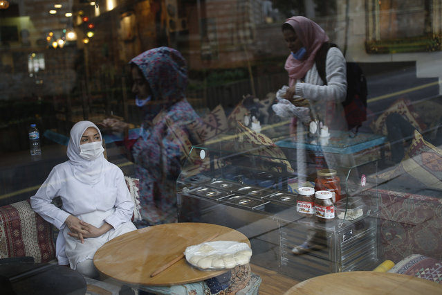 In this Wednesday, March 25, 2020, file photo, a customer wearing a protective mask due to the coronavirus outbreak, waits sits on a table of a restaurant, in central Istanbul. Turkey has charted its own course to navigate the coronavirus pandemic, with a more relaxed lockdown than its neighbors in Europe and the Middle East. Citing concerns about the economy, Turkish President Recep Tayyip Erdogan has so far resisted calls for more drastic measures to stem the contagion. (Photo by Emrah Gurel/AP Photo/File)