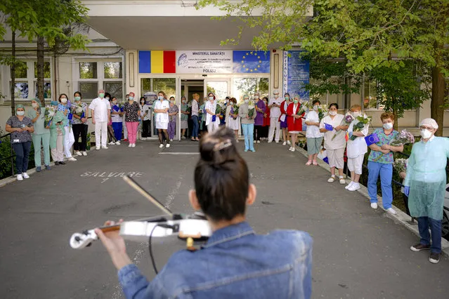 Medical staff of the Polizu maternity hospital listen to a violinist playing to entertain them and the patients in Bucharest, Romania, Tuesday, April 28, 2020. Raluca Raducanu, a young violinist, played a mix of rock and classical pieces during an under one hour performance outside the hospital. (Photo by Andreea Alexandru/AP Photo)