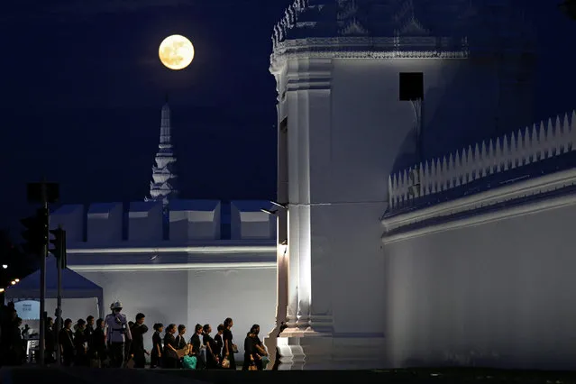 The moon rises as well-wishers line up to pay respect to late Thai King Bhumibol Adulyadej at the Grand Palace in Bangkok, Thailand, October 5, 2017. (Photo by Athit Perawongmetha/Reuters)