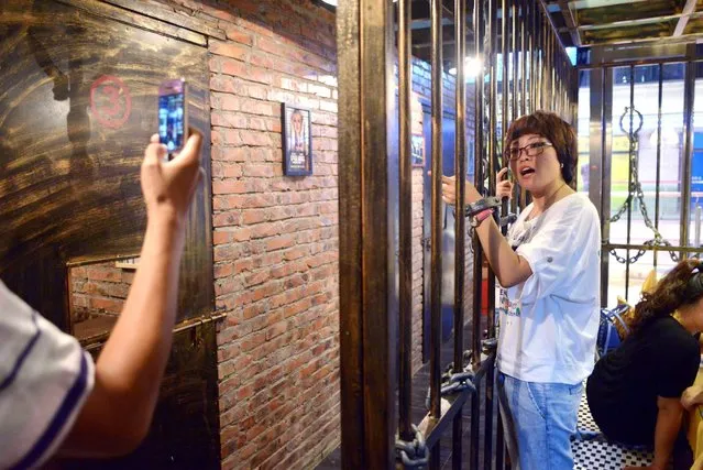 This picture taken on September 9, 2014 shows a family taking a photo before their dinner at a prison themed restaurant in Tianjin. (Photo by Wang Zhao/AFP Photo)