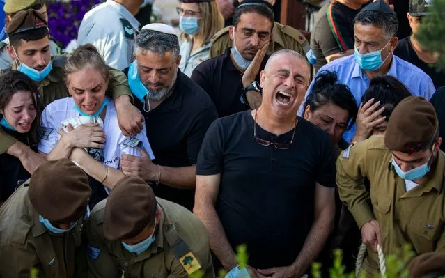 Baruch, right, and Nava, left, parents of Israeli army Staff Sgt. Amit Ben-Yigal grieve during his funeral as soldiers and family wear face masks to protect against the spread of the coronavirus in Beer Yaakov, Israel, Tuesday, May 12, 2020. Ben Ygal, 21, was killed early Tuesday during a West Bank arrest raid when a rock thrown off a rooftop struck him in the head, the military said, capping a surge in violence ahead of a visit to the region by the U.S. secretary of state. (Photo by Ariel Schalit/AP Photo)