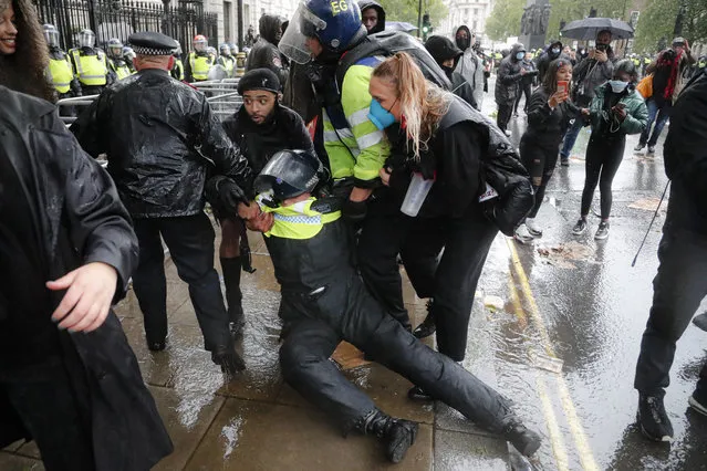 A police officer who was injured when falling of a horse during scuffles with demonstrators at Downing Street during a Black Lives Matter march in London, Saturday, June 6, 2020, is dragged by colleagues, as people protest against the killing of George Floyd by police officers in Minneapolis, USA. Floyd, a black man, died after he was restrained by Minneapolis police while in custody on May 25 in Minnesota. (Photo by Frank Augstein/AP Photo)