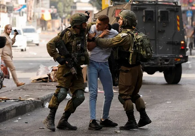 Members of the Israeli forces detain a Palestinian man amid clashes, in Hebron, in the Israeli-occupied West Bank on October 12, 2022. (Photo by Mussa Qawasma/Reuters)