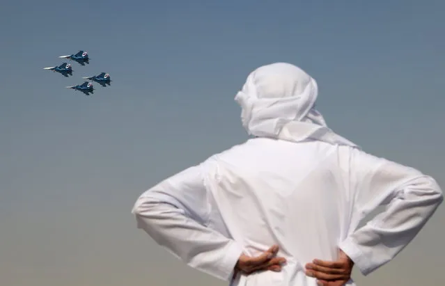 A man in an Arab dress watches Sukhoi Su-30SM jet fighters of the Russkiye Vityazi (Russian Knights) aerobatic team perform stunts at the 2017 Dubai Airshow, a biennial international aerospace show in Dubai, United Arab Emirates on November 12, 2017. (Photo by Marina Lystseva/TASS)