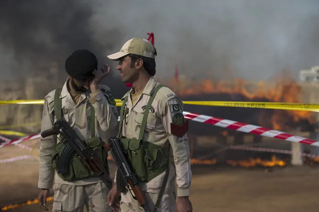 Officials of Pakistan's Anti-Narcotic Force (ANF) stand guard before a pile of confiscated drugs burned in Islamabad, Pakistan, Tuesday, December 5, 2017. Pakistan is taking strict measures to stop drug trafficking from neighboring Afghanistan and Pakistani tribal areas. (Photo by B.K. Bangash/AP Photo)