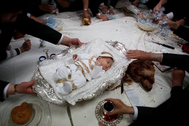 The great-grandson of the spiritual leader of the ultra-Orthodox Jewish Hassidic Lelover dynasty lies on a table during a religious ceremony, called “Pidyon Ha'ben”, or the “redemption of the first-born son”, originating from the biblical story of Moses on Mount Sinai, whereby the father of the baby makes a symbolic offering, including jewellery and sweets, to a Kohen or Jewish priest, in Jerusalem's neighbourhood of Mea Shearim September 1, 2016. (Photo by Ronen Zvulun/Reuters)