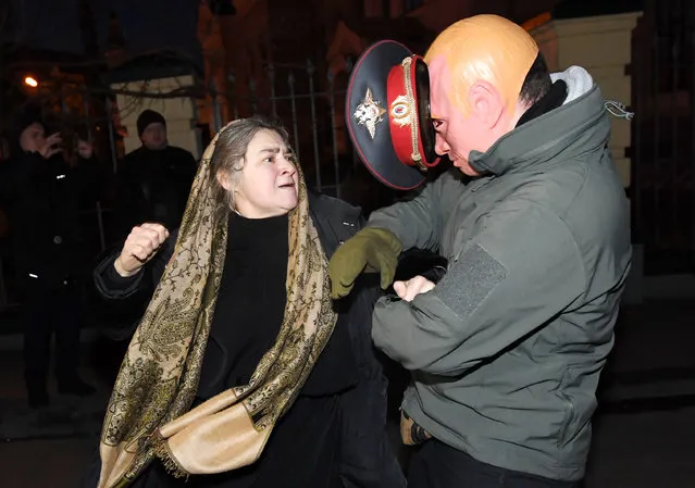 A pro-Russian woman, fanatical believer of Ukrainian Orthodox Church (Moscow Patriarchy), attacks an activist mocking Russian President Vladimir Putin during a protest of Ukrainian nationalists at Kiev-Pecherskaya Lavra Cathedral in Kiev on January 8, 2018. After Ukraine gained independence in 1991, a conflict erupted between the Ukrainian Orthodox Church backed by Moscow and a breakaway Kiev-based Ukrainian Orthodox Church now led by Patriarch Filaret. The rift was highlighted earlier this month after it was reported in Ukraine a bereaved father punched a priest from the Moscow-led church after he allegedly refused to bury his young son who died in a freak accident. (Photo by Sergei Supinsky/AFP Photo)
