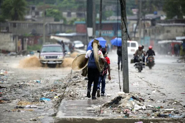 People walk along a street during the passage of Tropical Storm Laura, in Port-au-Prince, Haiti on August 23, 2020. (Photo by Andres Martinez Casares/Reuters)