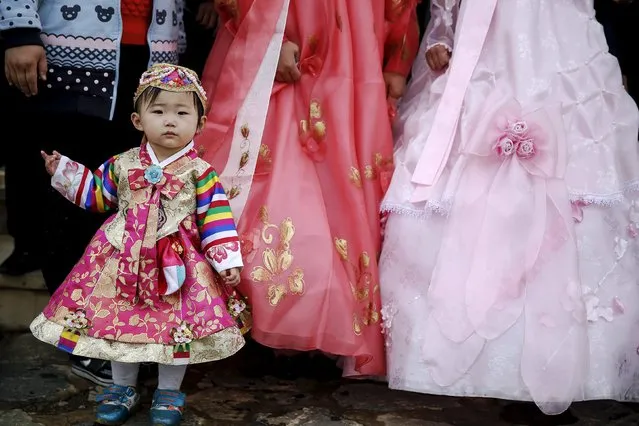 A child dressed in traditional clothes poses with newly-wed couple at Pyongyang Folk Park October 11, 2015. (Photo by Damir Sagolj/Reuters)