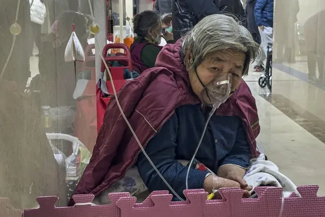 An elderly patient receives an intravenous drip while using a ventilator in the hallway of the emergency ward at a hospital in Beijing, Thursday, January 5, 2023. Patients, most of them elderly, are lying on stretchers in hallways and taking oxygen while sitting in wheelchairs as COVID-19 surges in China's capital Beijing. (Photo by Andy Wong/AP Photo)