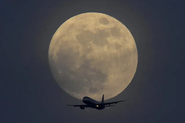 A British Airways aicraft flies infront of a full moon over London, Britain, January 30, 2018. (Photo by Toby Melville/Reuters)
