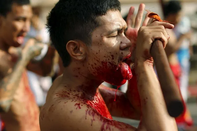 A devotee of the Chinese Samkong Shrine cuts his tongue with an axe during a procession celebrating the annual vegetarian festival in Phuket, Thailand, October 16, 2015. (Photo by Jorge Silva/Reuters)