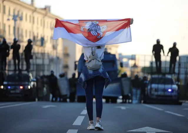 An opposition supporter holds a historical white-red-white flag of Belarus in front of law enforcement officers during a rally to demand the resignation of Belarusian President Alexander Lukashenko more than a month after the disputed presidential election, in Minsk, Belarus on September 20, 2020. (Photo by Tut.By via Reuters)