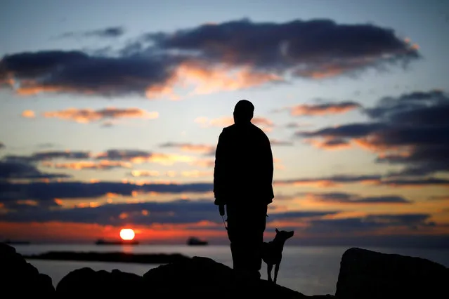 A man watches the sunset with his dog on a breakwater, along the shore of the Mediterranean Sea in Ashkelon, Israel January 9, 2018. (Photo by Amir Cohen/Reuters)