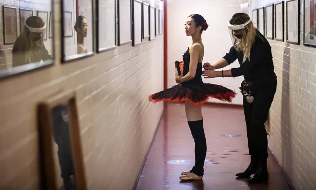 A member of the back stage staff wears PPE as she helps a ballerina from Northern Ballet prepares in a dressing room at Leeds Playhouse in West Yorkshire on October 21, 2020, ahead of Northern Ballet's first live performances in more than seven months. (Photo by Danny Lawson/PA Images via Getty Images)