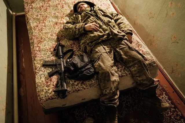 A Ukraine Army serviceman rests laying on a bed after returning from the frontline, at a rest and recovery base, in the Donetsk region on February 24, 2023, on the first anniversary of the Russian invasion of Ukraine. (Photo by Yasuyoshi Chiba/AFP Photo)