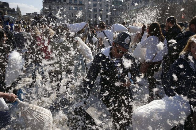 People, including a man wearing a toy traditional British police helmet, take part in a pillow fight in Trafalgar Square in London, Saturday, April 6, 2013.  A coordinated set of pillow fights took place in cities around the world on Saturday. The organizers of the London event stated there are only two rules, don't hit anyone with a camera and don't hit anyone without a pillow. (Photo by Matt Dunham/AP Photo)