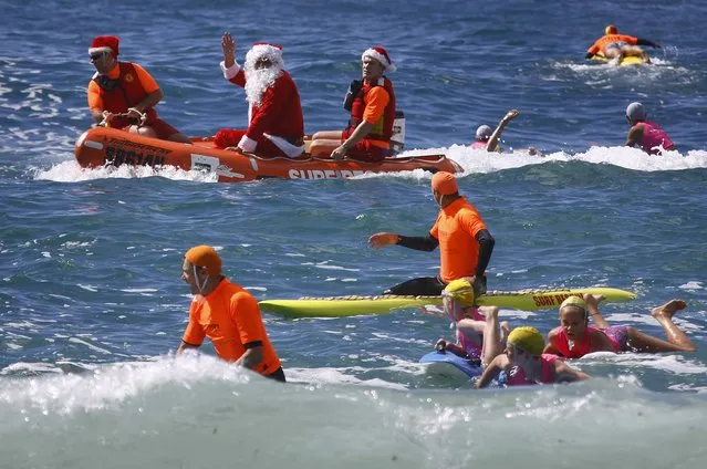 A man dressed as Santa Claus waves as he arrives in an inflatable rescue boat (IRB), as part of Christmas celebrations for the Coogee Surf Lifesaving Club, at Sydney's Coogee Beach December 14, 2014. (Photo by David Gray/Reuters)