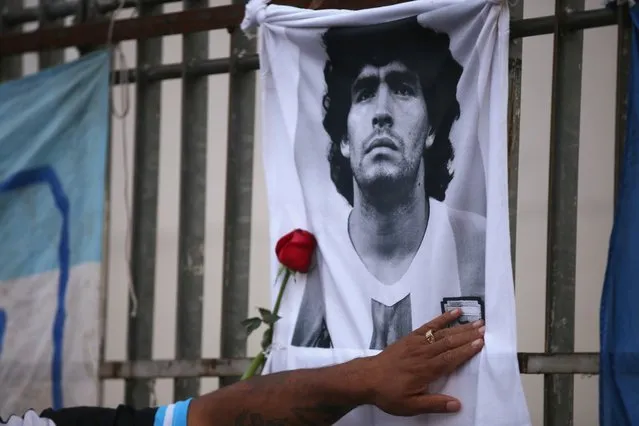 A rose is placed next to a banner of Argentine soccer great Diego Maradona as fans gather to mourn his death, at the Obelisk of Buenos Aires, Argentina on November 25, 2020. Millions of fans paid tribute and Argentina was plunged into mourning on November 25 as Maradona, one of the greatest footballers of all time, died aged 60 after years of drug and alcohol problems. (Photo by Agustin Marcarian/Reuters)