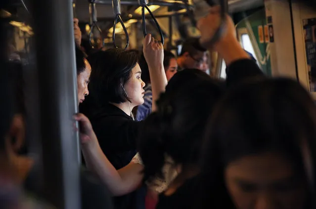 In this October 11, 2017, photo, passengers dress in black in honor of the late King of Thailand as they ride the train in Bangkok, Thailand. (Photo by Wally Santana/AP Photo)