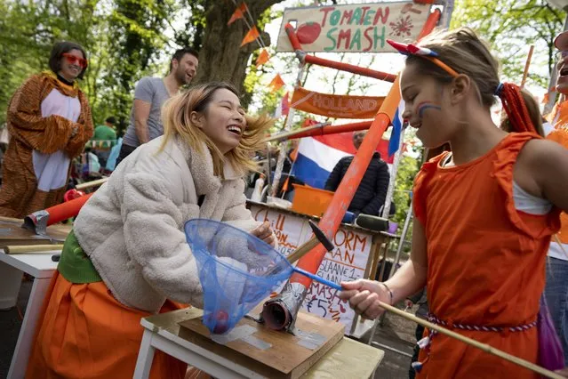 A woman reacts after failing to smash a tomato in a game as people celebrate King's Day in Amsterdam, Netherlands, Thursday, April 27, 2023. The Netherlands celebrated the 56th birthday of King Willem-Alexander on Thursday with street markets, parties and pastries, even as polls showed the monarch's popularity declining. (Photo by Peter Dejong/AP Photo)