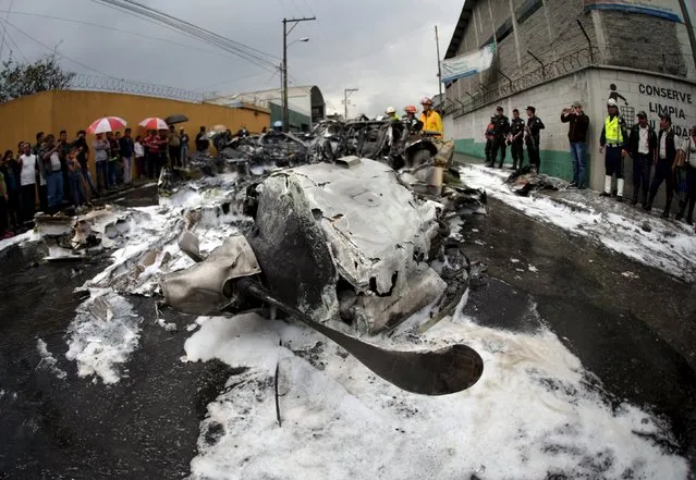 Rescuers and police officers stand around the remains of an aircraft crash in Guatemala City, November 21, 2015. The aircraft crashed after takeoff from La Aurora International Airport, with two crew members taken to hospital with minor injuries, local media reported. (Photo by Jorge Dan Lopez/Reuters)