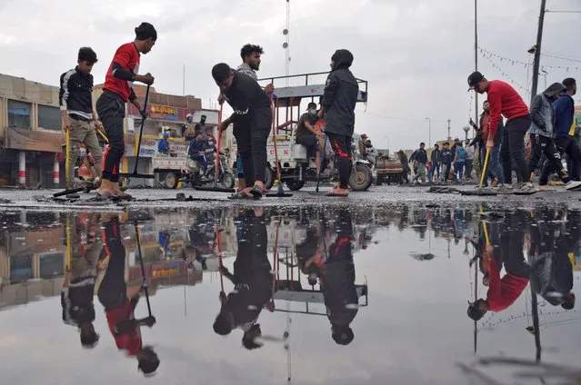 This picture taken on November 28, 2020 shows a view of people cleaning up at a protest site in Habboubi Square in Iraq's southern city of Nasiriyah. Anti-government protesters defied lockdowns and the threat of violence to demonstrate on November 28 in several Iraqi cities. In the southern hotspot of Nasiriyah, anti-government activists accused supporters of populist Shiite cleric Moqtada Sadr of shooting at them and torching their tents in their main gathering place of Habboubi Square late the day before. Nasiriyah was a major hub for the protest movement that erupted last year against a government seen by demonstrators as corrupt, inept and beholden to neighbouring Iran. (Photo by Asaad Niazi/AFP Photo)