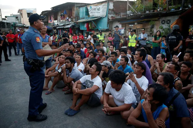 A police officer talks to male residents who are rounded up during an anti-drugs operation in Pasig, Metro Manila in the Philippines, November 9, 2016. (Photo by Erik De Castro/Reuters)