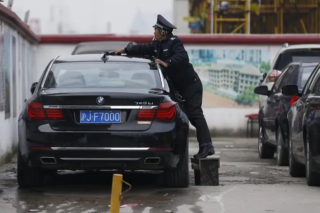 A security guard cleans a car on a street in Shanghai, China, December 14, 2015. (Photo by Aly Song/Reuters)