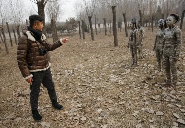 Chinese artist Liu Bolin direct his models painted in camouflage colours to blend in with the background for his artwork “Dongji”, or Winter Solstice, on the second day after China's capital Beijing issued its second ever “red alert” for air pollution, in Beijing, China, December 20, 2015. (Photo by Kim Kyung-Hoon/Reuters)
