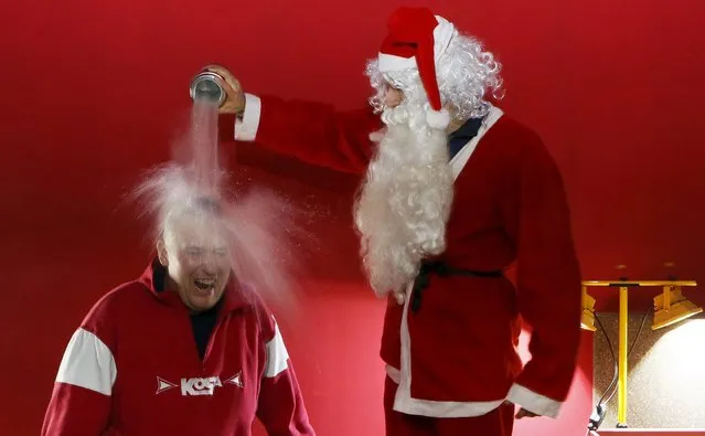 Ivan Timofeenko, co-founder of “Newton Park”, a private interactive museum of science, dressed as Santa Claus, pours liquid nitrogen, bearing the temperature of about minus 196 degrees Celsius (minus 320.8 degrees Fahrenheit), on the head of visitor Dmitry Shilov during the “Arctic” scientific show for school children at the “Square of Peace” museum centre in the Siberian city of Krasnoyarsk, Russia, December 24, 2015. (Photo by Ilya Naymushin/Reuters)