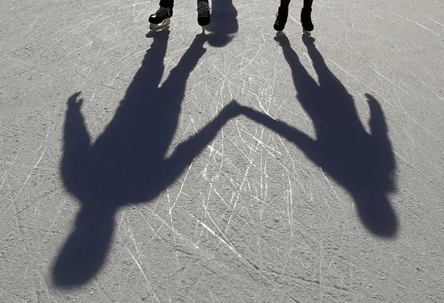 A couple casts shadows on the ice as they hold hands and skate on an outdoor rink in Millennium Park in Chicago, Illinois, United States, November 24, 2015. (Photo by Jim Young/Reuters)