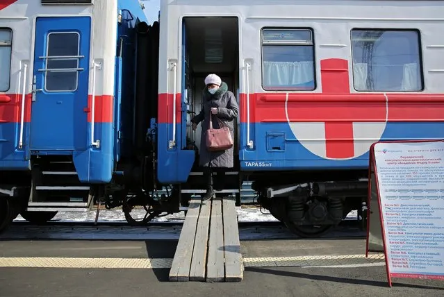 A woman wearing a protective face mask leaves a carriage of the Academician Fyodor Uglov medical train providing health services, including vaccination against the coronavirus, at a railway station in the town of Tulun in Irkutsk Region, Russia on March 16, 2021. (Photo by Evgeny Kozyrev/Reuters)