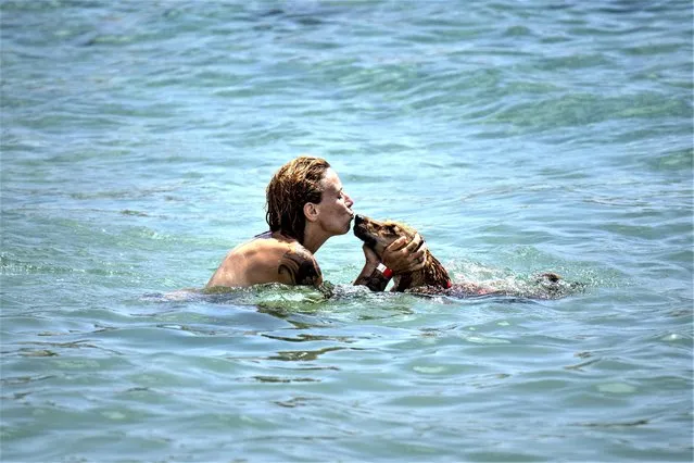 A woman kisses her dog during swimming on a beach in Barcelona, Spain, Monday, July 17, 2023. Spain's Aemet weather agency said a heatwave starting Monday “will affect a large part of the countries bordering the Mediterranean” with temperatures in some southern areas of Spain exceeding 42-44 ºC. (Photo by Emilio Morenatti/AP Photo)