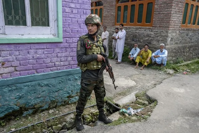 An Indian army soldier stands guard outside the house of his colleague Waseem Sarvar Bhat, who was killed in a gun battle with suspected rebels, as relatives and villagers wait for the body to arrive in Bandipora, north of Srinagar, Indian controlled Kashmir, Saturday, August 5, 2023. (Photo by Dar Yasin/AP Photo)