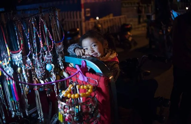 This picture taken on September 9, 2016 shows a girl playing on a souvenir vendors cart  in the regional capital Lhasa, in China's Tibet Autonomous Region.
The traditional teahouses and fashion boutiques of Bayi are the among the liveliest districts of Lhasa, and owned and patronised by both Tibetans and Han Chinese. But some say increasing prosperity is just Beijing buying peace. (Photo by Johannes Eisele/AFP Photo)