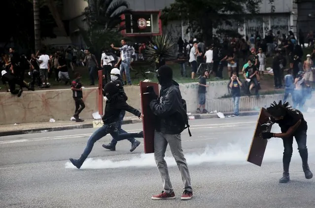 A demonstrator (L) protester kicks a teargas canister fired by riot police during a protest against fare hikes for city buses in Sao Paulo, Brazil, January 8, 2016. (Photo by Nacho Doce/Reuters)