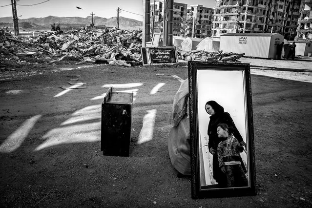 And Life Rises by Younes Khani Someeh Soflaei, Iran, winner of the built environment prize. A woman and her young daughter stand next to their damaged belongings, which were recovered from the rubble of their house in Sarpol-e Zahab. Mehr residential complex stands ravaged in the background after a devastating earthquake in 2017 killed more than 600 people. (Photo by Younes Khani Someeh Soflaei/2018 Ciwem environmental photographer of the year 2018)