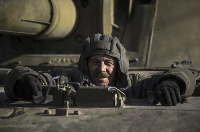A Ukrainian soldier smiles riding on a self-propelled artillery near Artemivsk, eastern Ukraine, Monday, Feb. 23, 2015. A Ukrainian military spokesman says continuing attacks from rebels are delaying Ukrainian forces' pullback of heavy weapons from the front line in the country's east. (AP Photo/Evgeniy Maloletka)